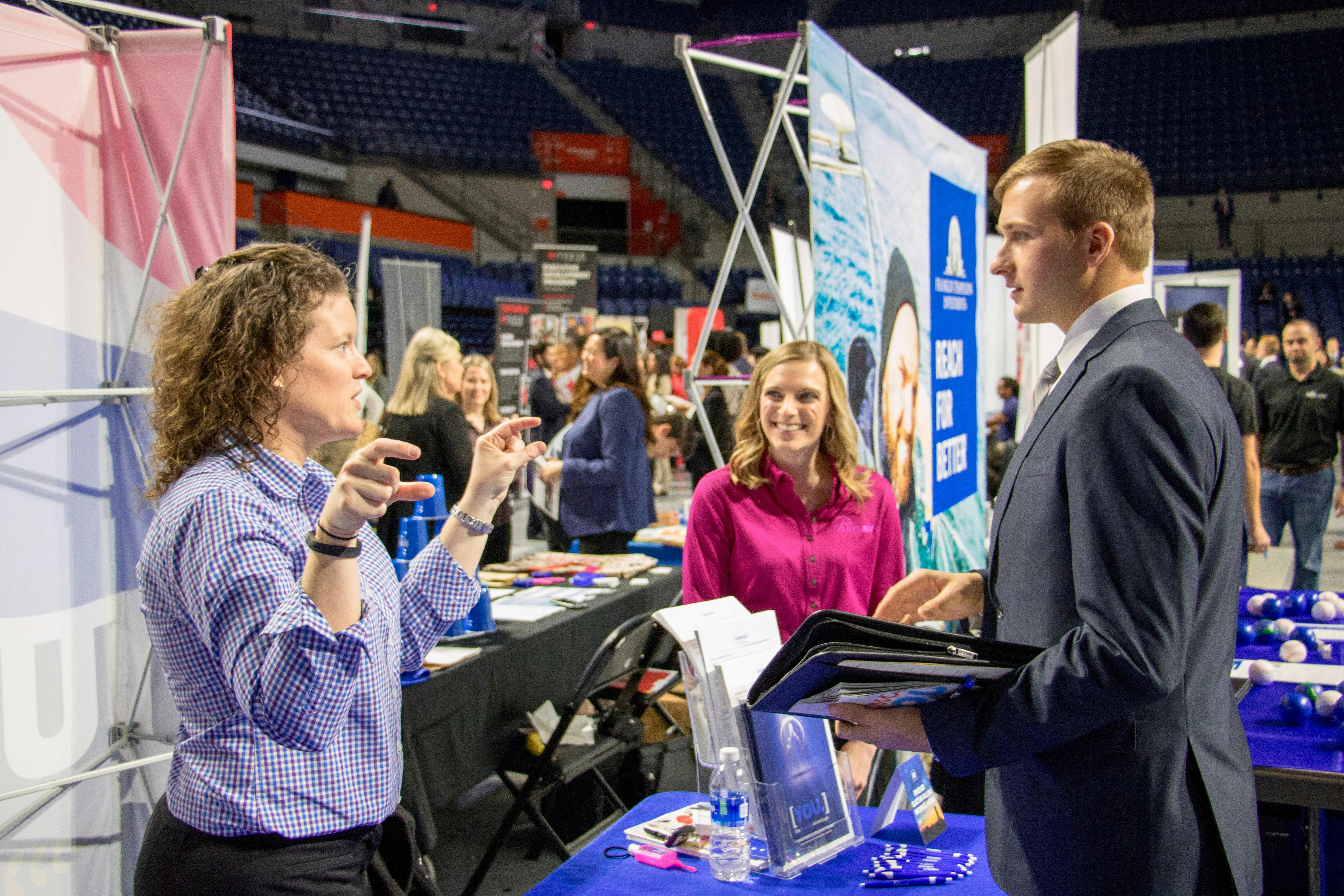 Representatives from Summit Holdings, Inc. speak to a student about the different opportunities at their company. Summit was one of the hundreds of firms and organizations present at Career Showcase in the Stephen C. O'Connell Center on Tuesday morning.