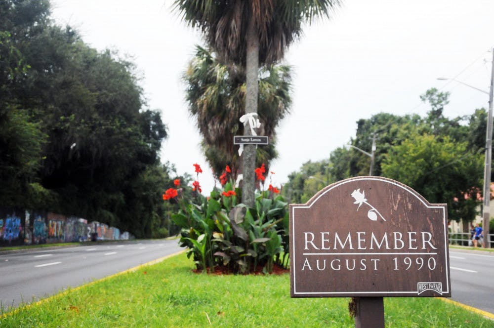 A sign that reads "Remember August 1990" stands in the median of Southwest 34th Street. Behind it stands five trees with white ribbons and the names of the five students killed by Danny Rolling. This week marked the 25th anniversary of the murders.