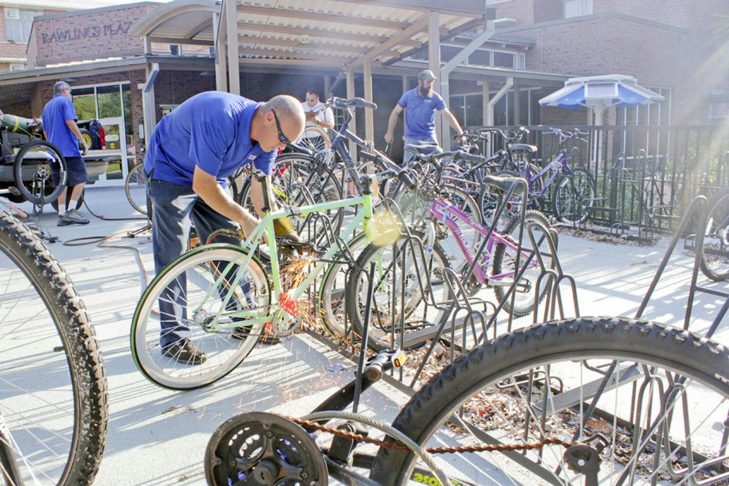 A UF employee removes a lock from an abandoned bicycle using a blowtorch outside Rawlings Hall.