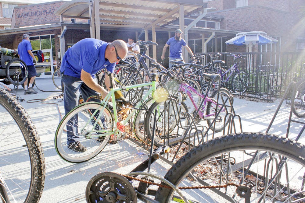 <p>A UF employee removes a lock from an abandoned bicycle using a blowtorch outside Rawlings Hall.</p>