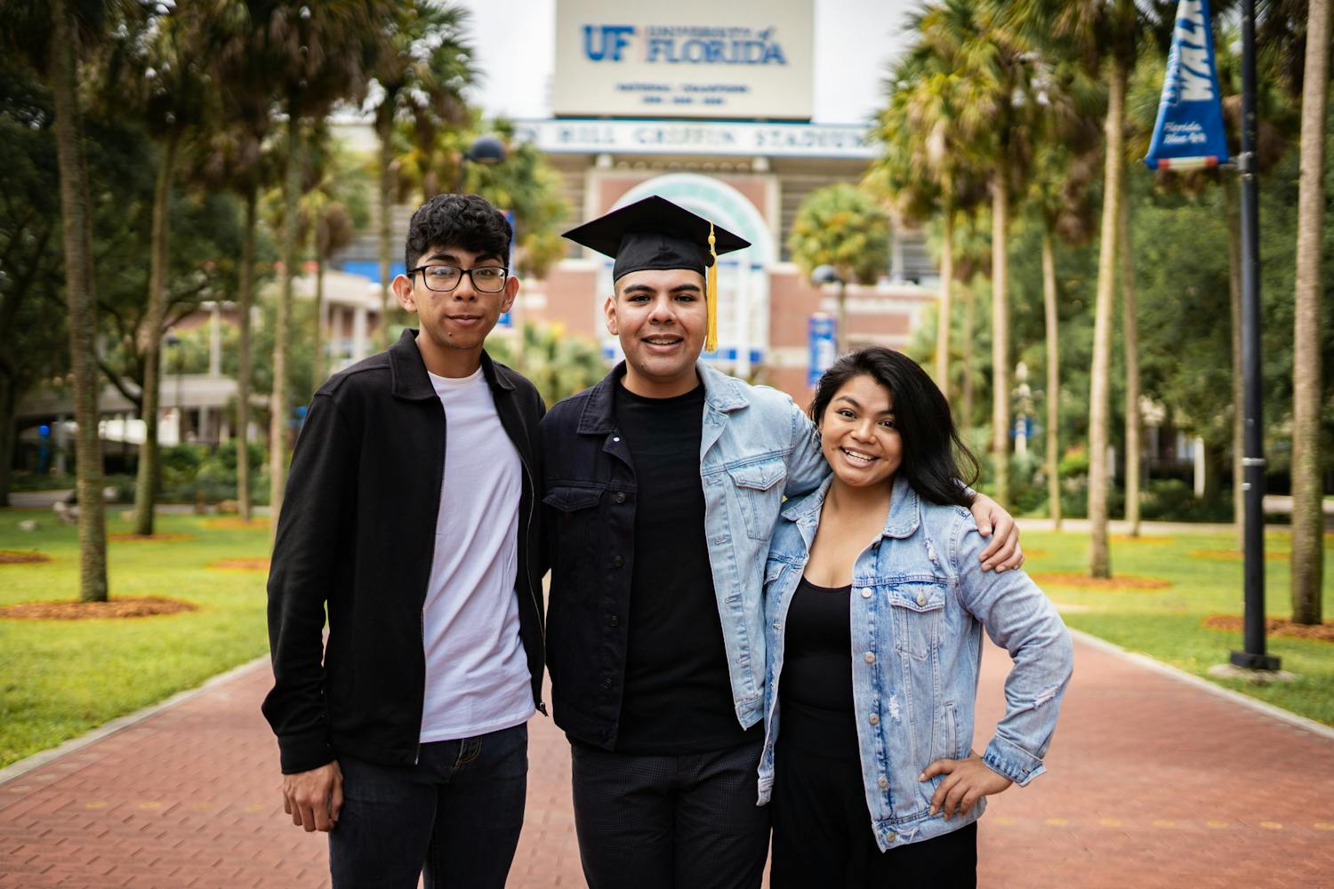 Jose Alvarez, center, and siblings David and Ismelda Alvarez, left and right, celebrate Jose’s graduation from the University of Florida in front of the Ben Hill Griffin Stadium. 