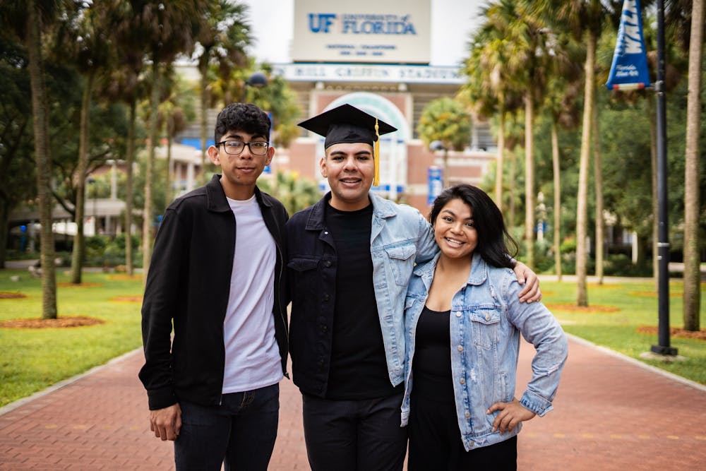 <p>Jose Alvarez, center, and siblings David and Ismelda Alvarez, left and right, celebrate Jose’s graduation from the University of Florida in front of the Ben Hill Griffin Stadium. </p>