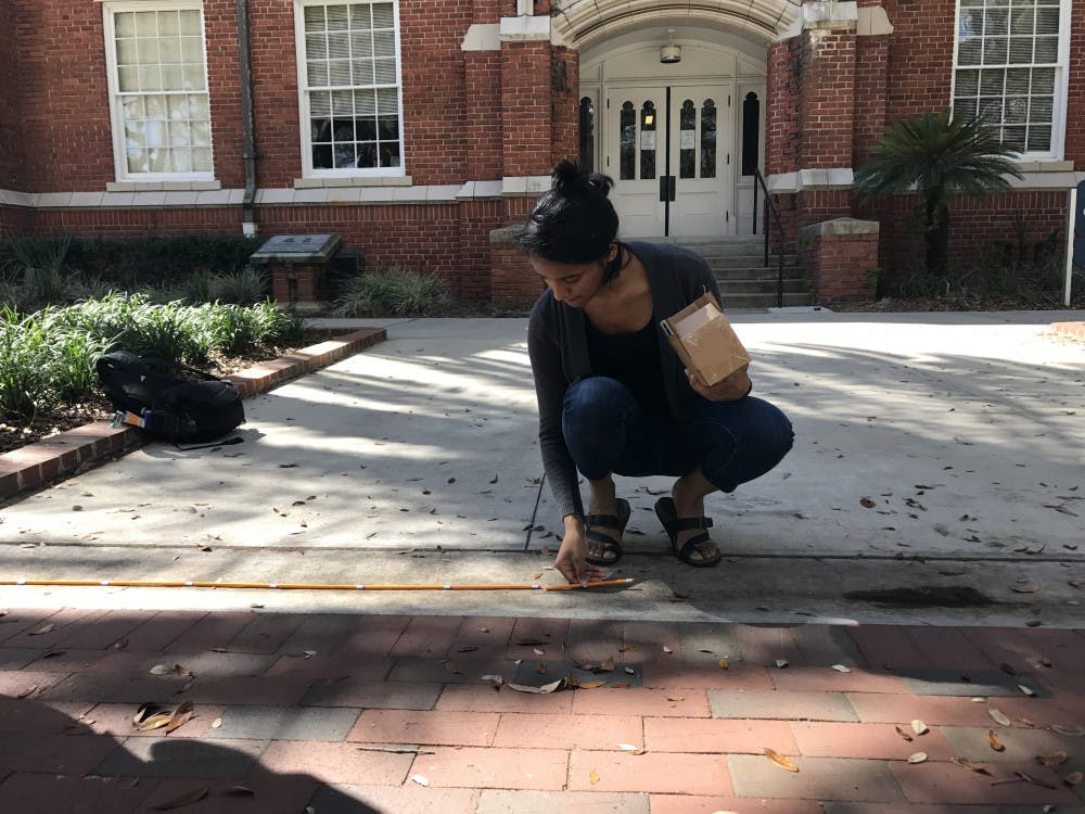 Sweta Madem, a 19-year-old UF biology freshman, helps lay down pencils Friday to set a world record for the longest line of pencils in succession. Madem said she heard about the event from a friend and decided to help out.