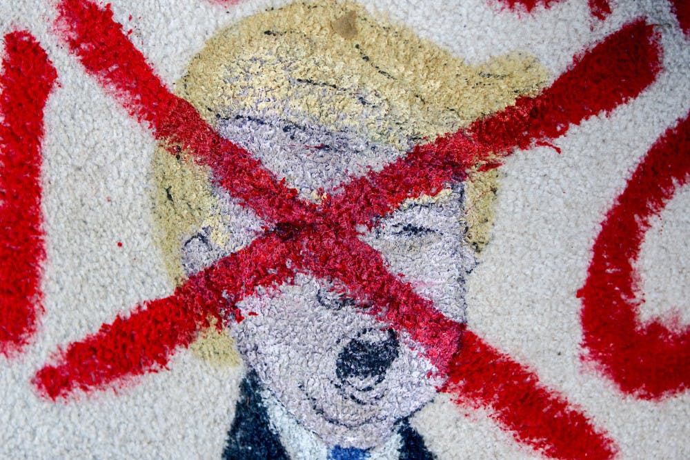 A painting of Donald Trump crossed out sits on the corner of University Avenue and Main Street during a protest of the results of the presidential election. The protest was one of six happening simultaneously on Thursday in Gainesville.