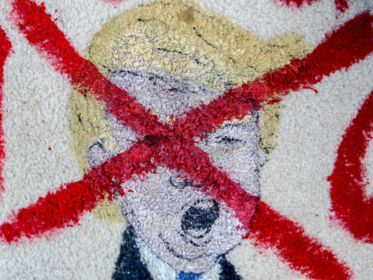 A painting of Donald Trump crossed out sits on the corner of University Avenue and Main Street during a protest of the results of the presidential election. The protest was one of six happening simultaneously on Thursday in Gainesville.