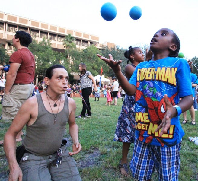Angel Gabrial, left, a teacher for the UF club Objects in Motion, gives Jason Winfrey, 7, some tips on juggling during a Labor Day festival at the Bo Diddley Community Plaza on Sunday night.