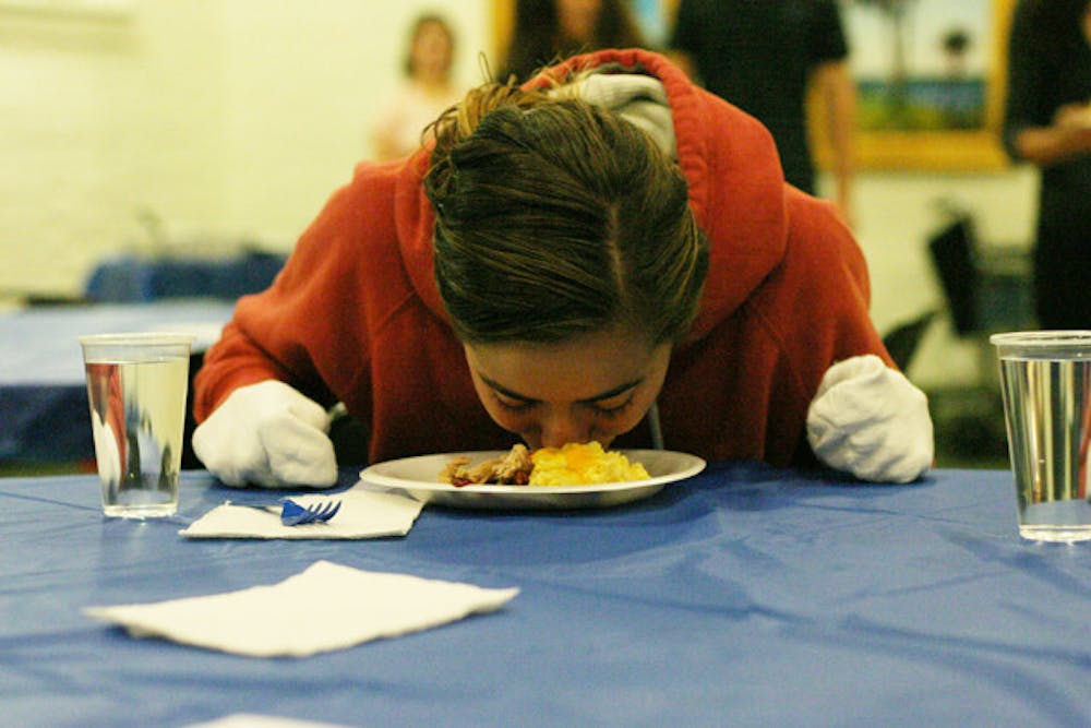 <p>Rebecca Shionis, a 19-year-old exploratory sophomore, eats dinner at Dining with Disabilities, catered by Kay Bros. BBQ, on Thursday. She had to eat dinner without the use of her hands.</p>
