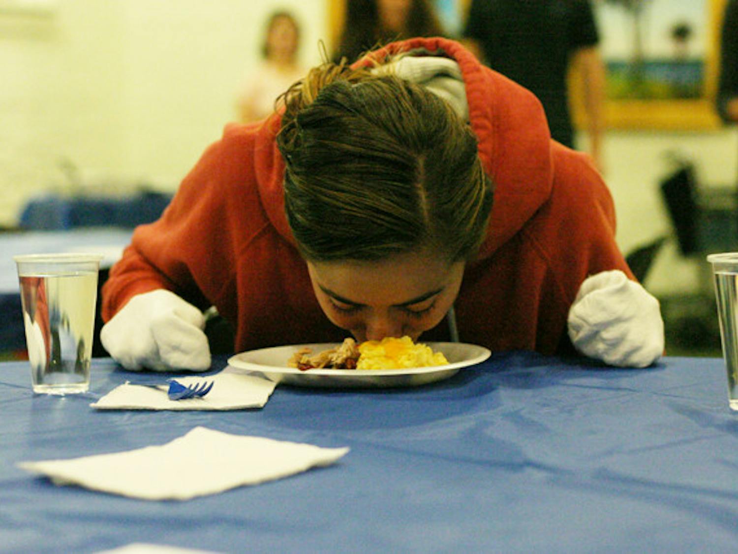Rebecca Shionis, a 19-year-old exploratory sophomore, eats dinner at Dining with Disabilities, catered by Kay Bros. BBQ, on Thursday. She had to eat dinner without the use of her hands.