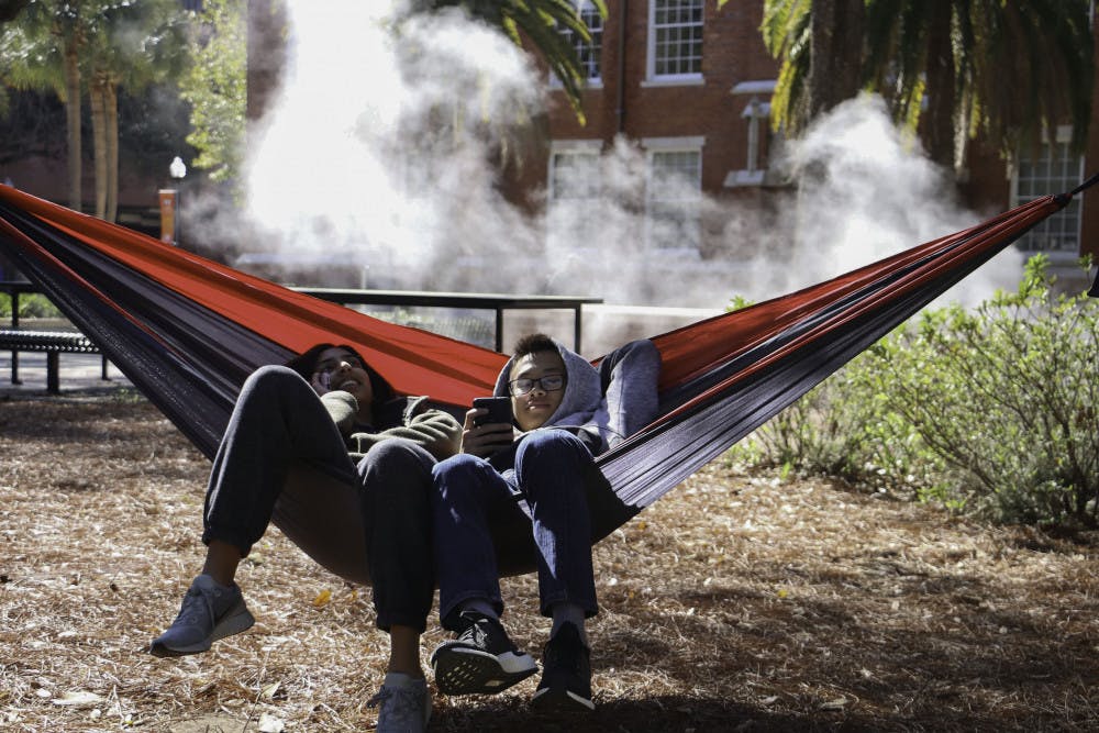 Zoya Mukherjee, an 18-year-old biology freshman, and Justin Ho, an 18-year-old computer science freshman, hang out near a barricaded manhole in the Plaza of the Americas Tuesday afternoon. Mukherjee said that it smells odd and Justin said that people do not like to sit near it.