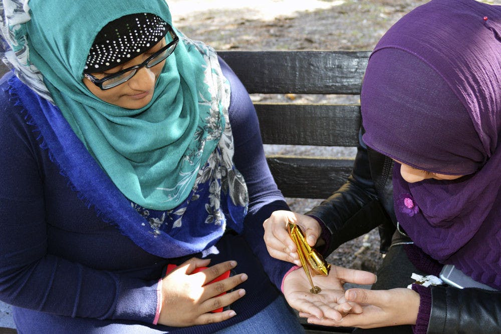 Najia Faddoul (left), a 19-year-old UF pre-pharmacy freshman, receives a henna tattoo from Sana Adalsha, a 19-year-old UF health science freshman, on Plaza of the Americas on Monday afternoon. Faddoul and Adalsha were offering henna tattoos to students to raise money for an event for high-schoolers in Orlando.