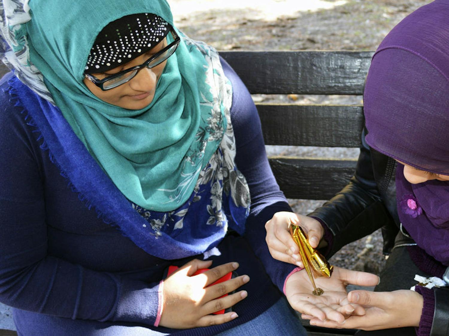 Najia Faddoul (left), a 19-year-old UF pre-pharmacy freshman, receives a henna tattoo from Sana Adalsha, a 19-year-old UF health science freshman, on Plaza of the Americas on Monday afternoon. Faddoul and Adalsha were offering henna tattoos to students to raise money for an event for high-schoolers in Orlando.