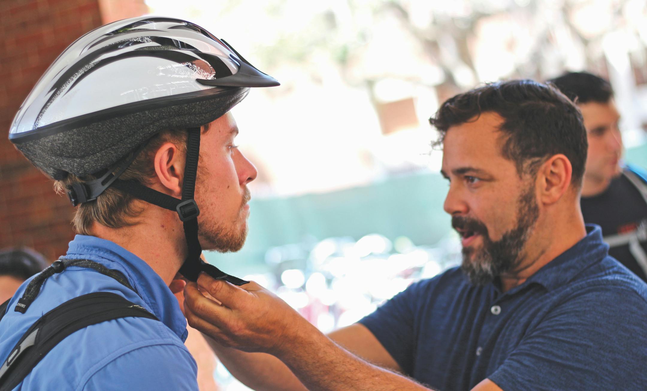 Conor MacDonnell, a 25-year-old UF soil and water science graduate student, receives a free bicycle helmet at the Keep Calm and Helmet On event held by UF Campus Diplomats, Alpha Epsilon Delta, Florida Pedestrian and Bicycling Safety and Regional Transit System. Paul Simpson, a 50-year-old PedBike Safety Resource Center employee, demonstrated how to properly strap a helmet.