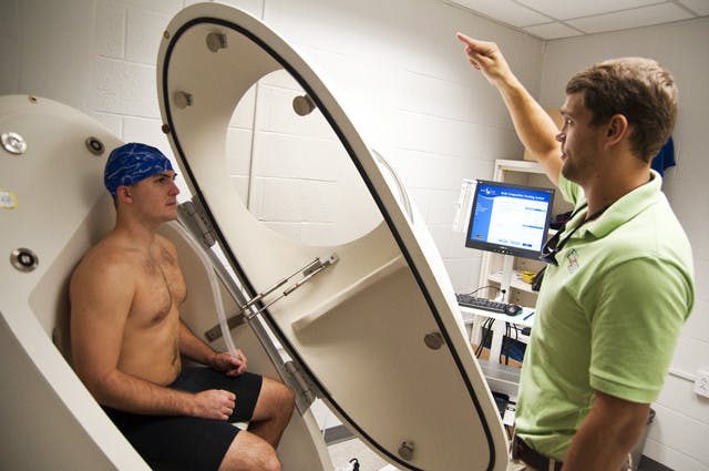 Food science graduate student Adam Knox, 23, sits in the Bod Pod as nutrition graduate student Blake Bartholomew, 23, explains how to use the breathing tube inside of the pod in order to properly calculate total body fat percentage.