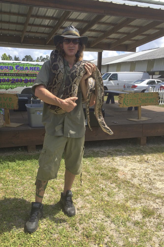 Devin Wheeler, an owner of Second Chance Reptile Sanctuary, holds a 16 foot Burmese python at the Waldo Farmers and Flea Market on Sunday. Wheeler started the sanctuary with Mitra Snyder to provide a home to reptiles that wouldn’t be able to survive in the wild.