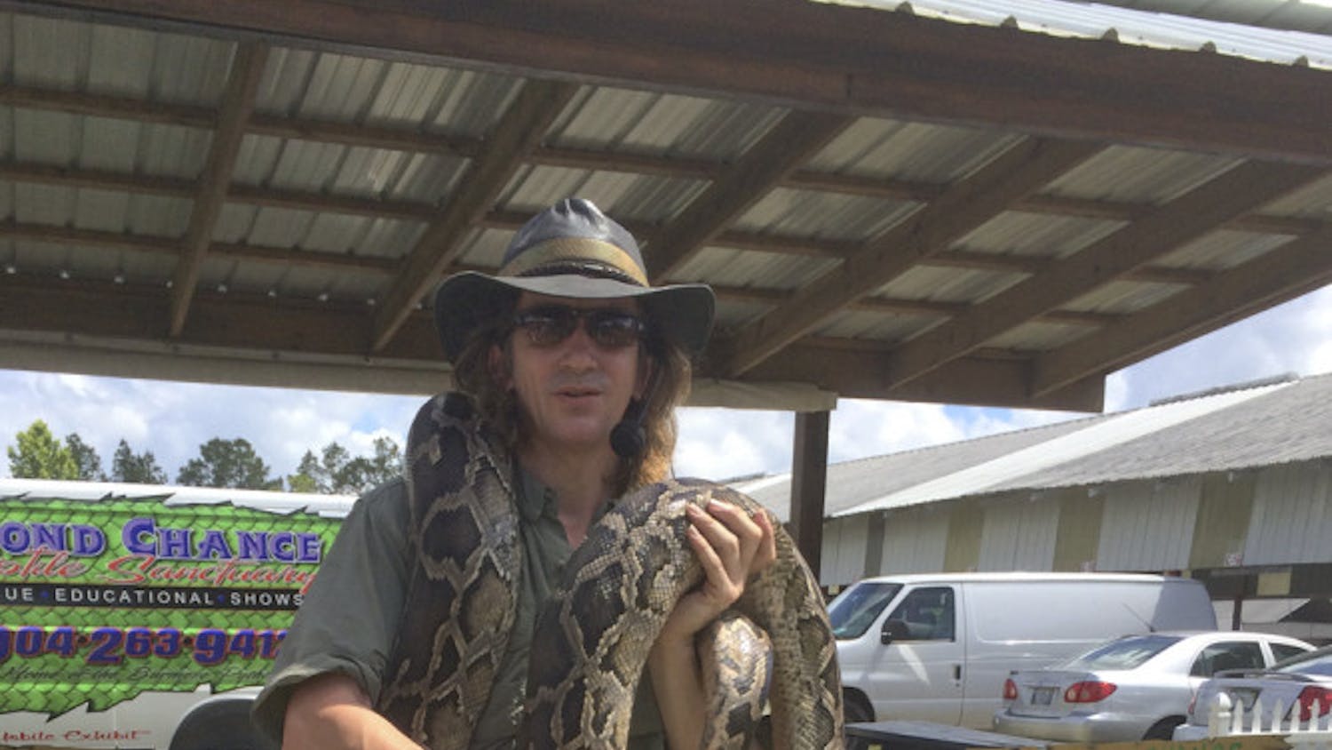 Devin Wheeler, an owner of Second Chance Reptile Sanctuary, holds a 16 foot Burmese python at the Waldo Farmers and Flea Market on Sunday. Wheeler started the sanctuary with Mitra Snyder to provide a home to reptiles that wouldn’t be able to survive in the wild.