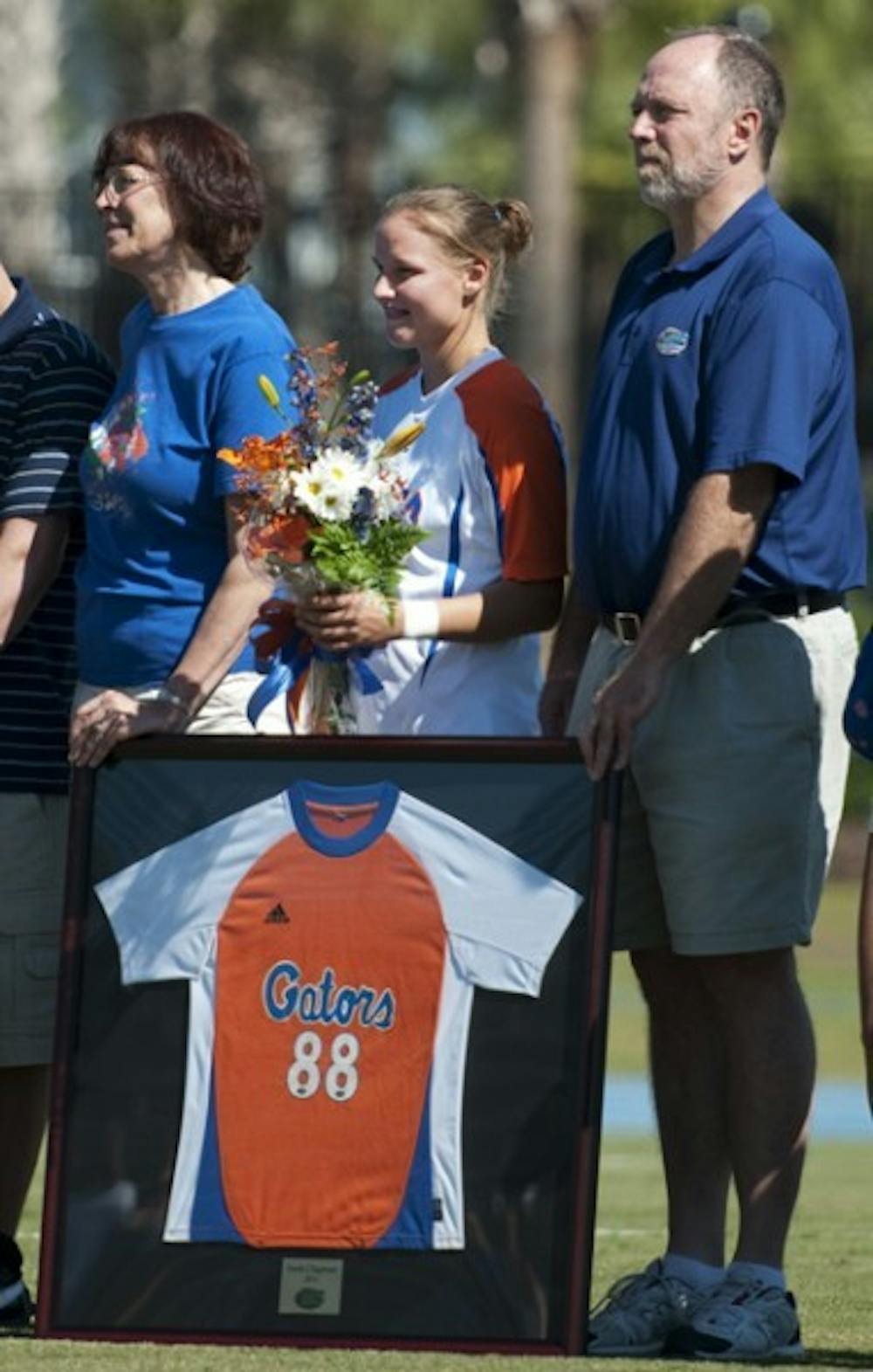 <p>Florida midfielder Sarah Chapman (center) is presented a framed jersey during Florida’s Senior Day on Oct. 23 as parents Rick (right) and Lynn (left) look on.</p>