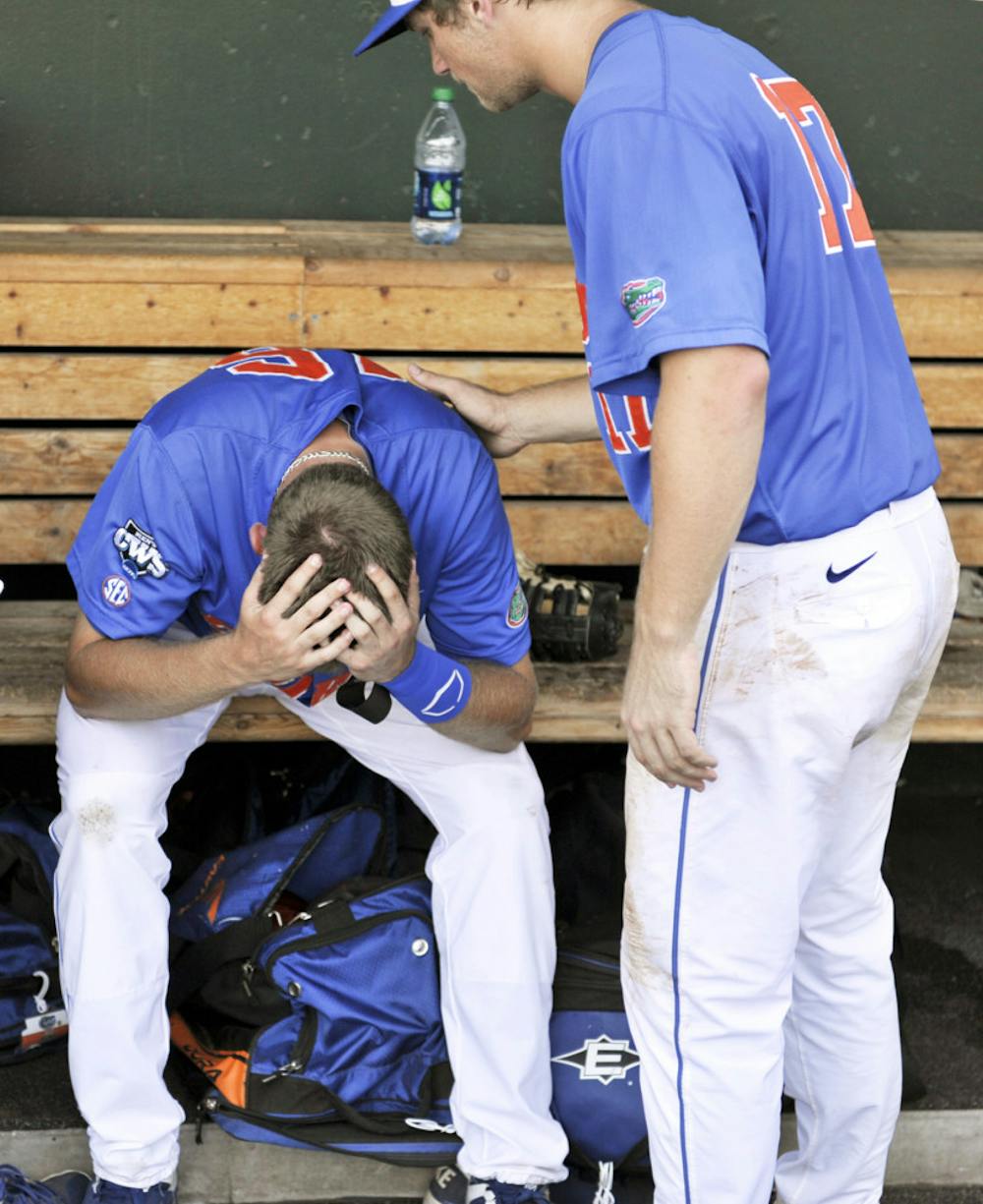 <p>Florida left fielder Justin Shafer (left) is consoled in the dugout by teammate Taylor Gushue after being eliminated from the College World Series on Monday.</p>