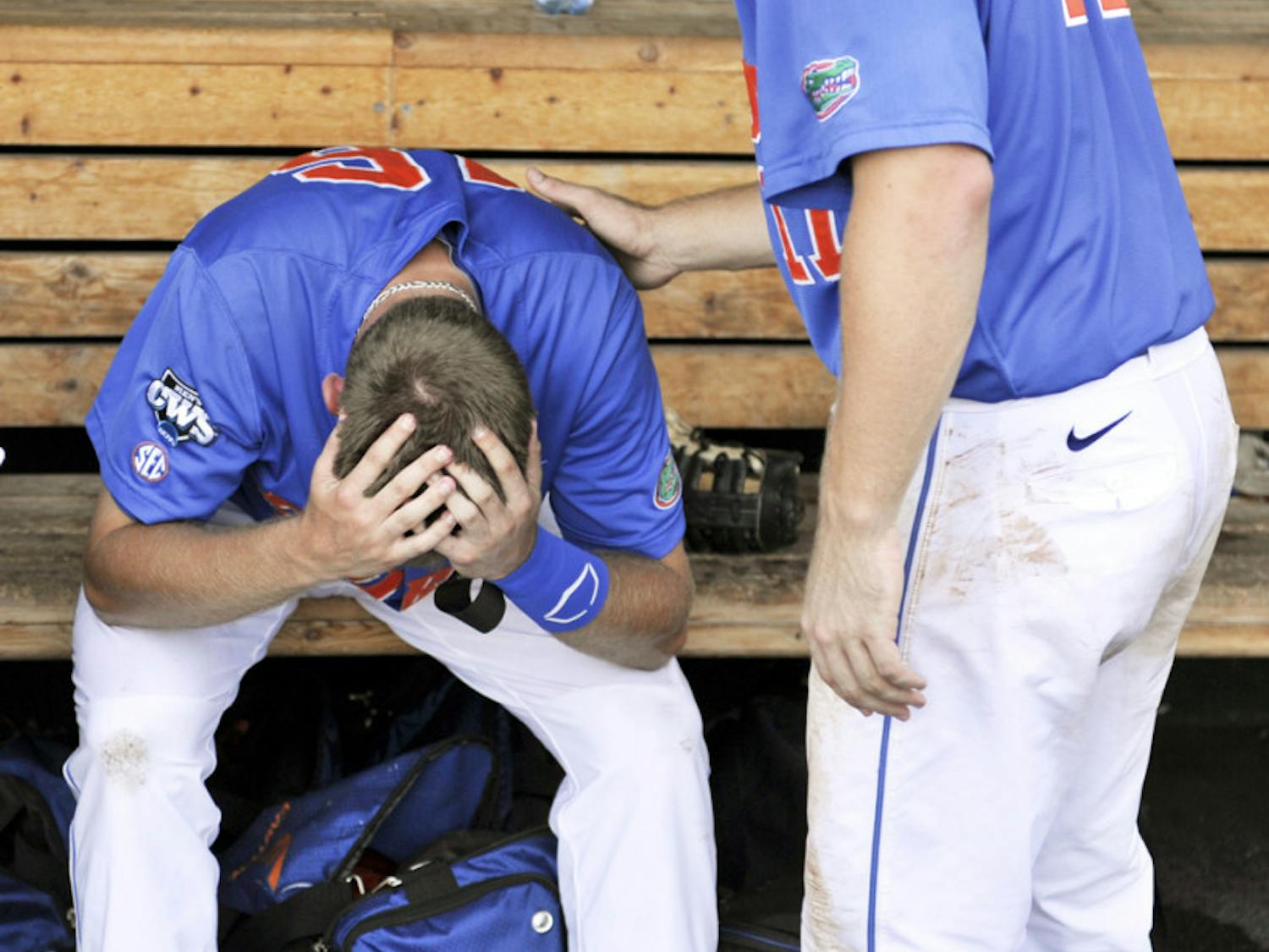 Florida left fielder Justin Shafer (left) is consoled in the dugout by teammate Taylor Gushue after being eliminated from the College World Series on Monday.