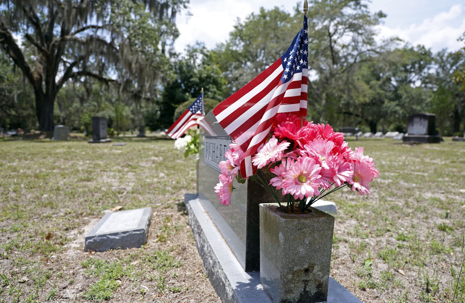 American flags stick out on the sides of a tombstone at Evergreen Cemetery in Gainesville, Fla., on Monday, May 27, 2024. 