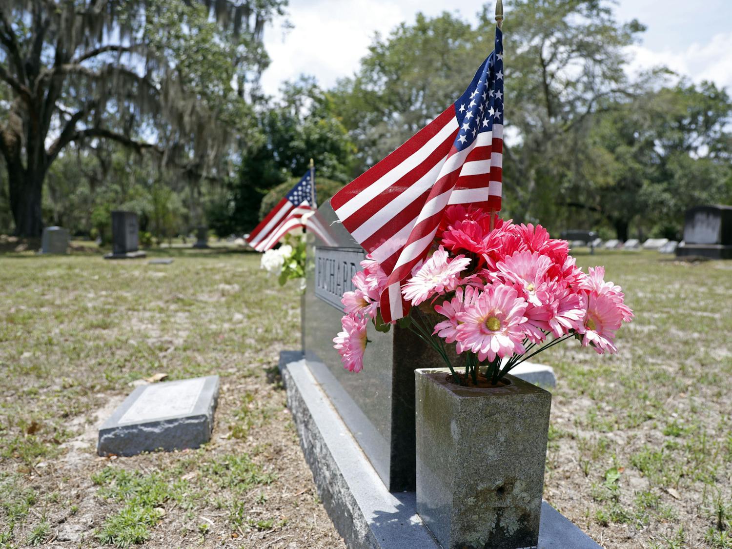 American flags stick out on the sides of a tombstone at Evergreen Cemetery in Gainesville, Fla., on Monday, May 27, 2024.