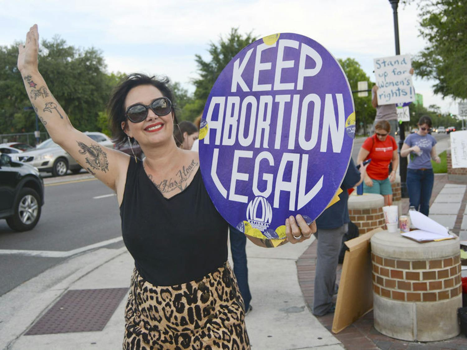 Su Mendez, an activist with the National Organization for Women and National Women’s Liberation, holds a sign and waves at passing vehicles at an abortion rights protest on University Avenue and 13th Street on Tuesday.
