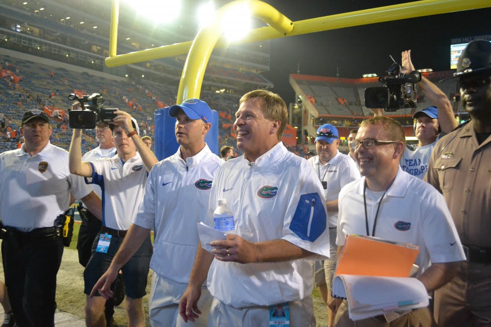 UF head football coach Jim McElwain (center) smiles as he walks off the field at Ben Hill Griffin Stadium following Florida's 61-13 win against New Mexico State Sept. 5, 2015