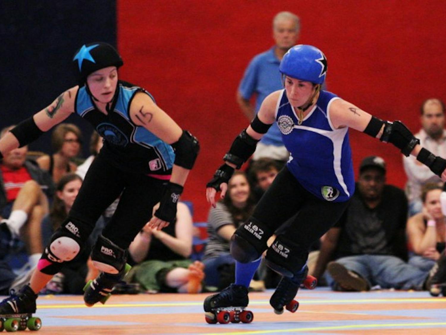 Lady Rider from the Blue Ridge Rollergirls and LeBrawn Maimes from the Gainesville Roller Rebels, both jammers, race across the rink. Identified by stars on their helmets, jammers are the only players who can score points for the team.