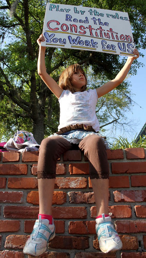 Alyssa, 9, holds a sign at the Tea Party rally in the Bo Diddley Downtown Community Plaza on Thursday afternoon.