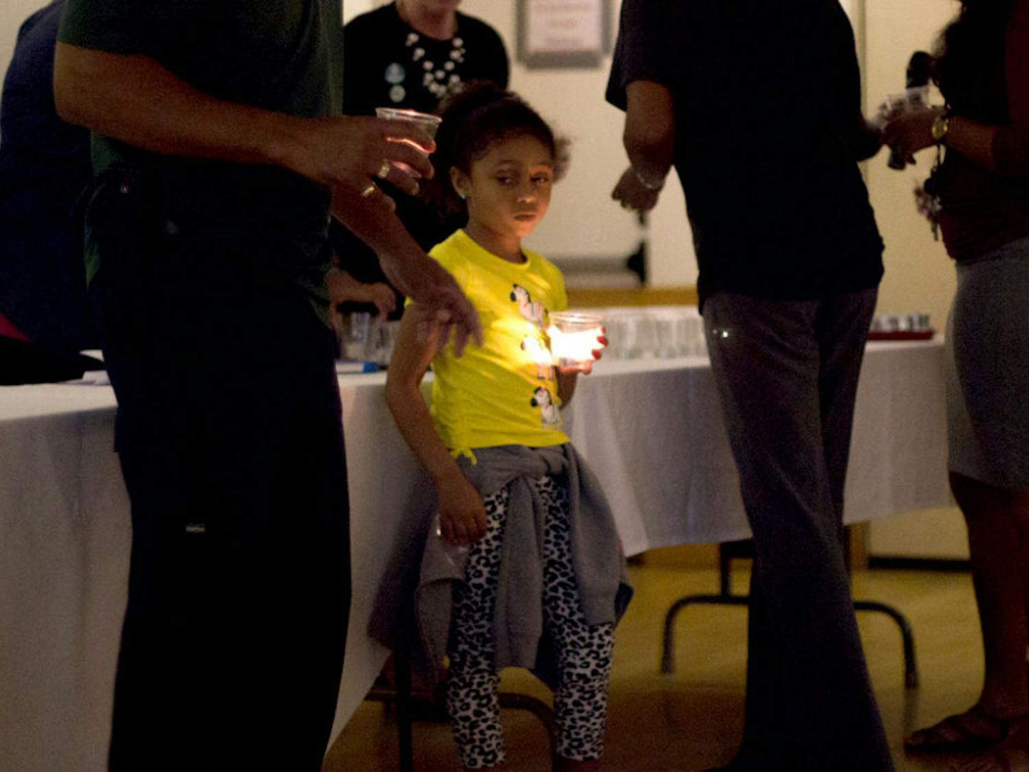 Giselle Lee, 5, holds a candle with her family. The annual vigil was held at the United Church of Gainesville and was dedicated to victims of crime and their families.