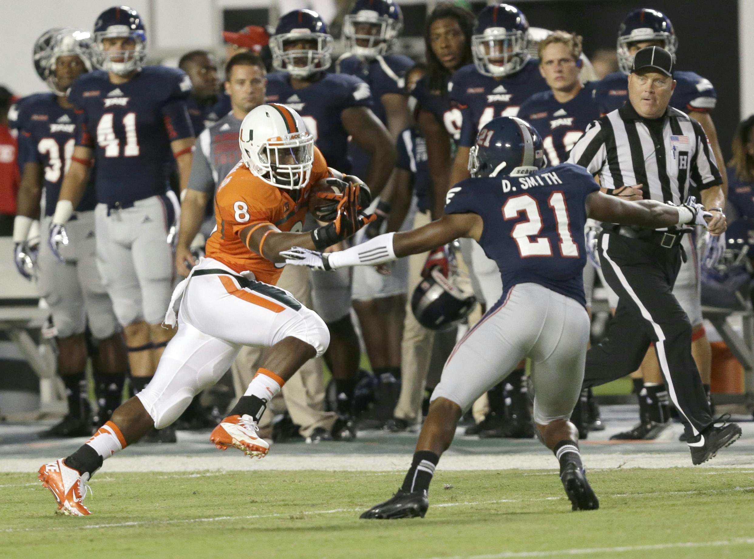 Miami running back Duke Johnson (8) attempts to avoid Florida Atlantic defensive back D’Joun Smith during the first half of an NCAA college football game on Aug. 30, in Miami Gardens, Fla. Johnson had a career-high 186 rushing yards and a touchdown as Miami defeated Florida Atlantic 34-6.