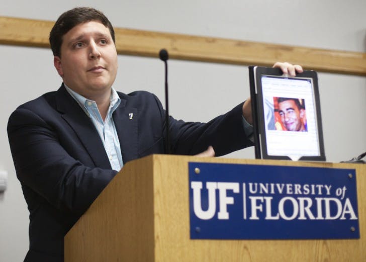 Student Body President Tj Villamil holds an iPad with an image of Christian Aguilar, an 18-year-old missing UF student, at the Student Senate meeting Tuesday night.