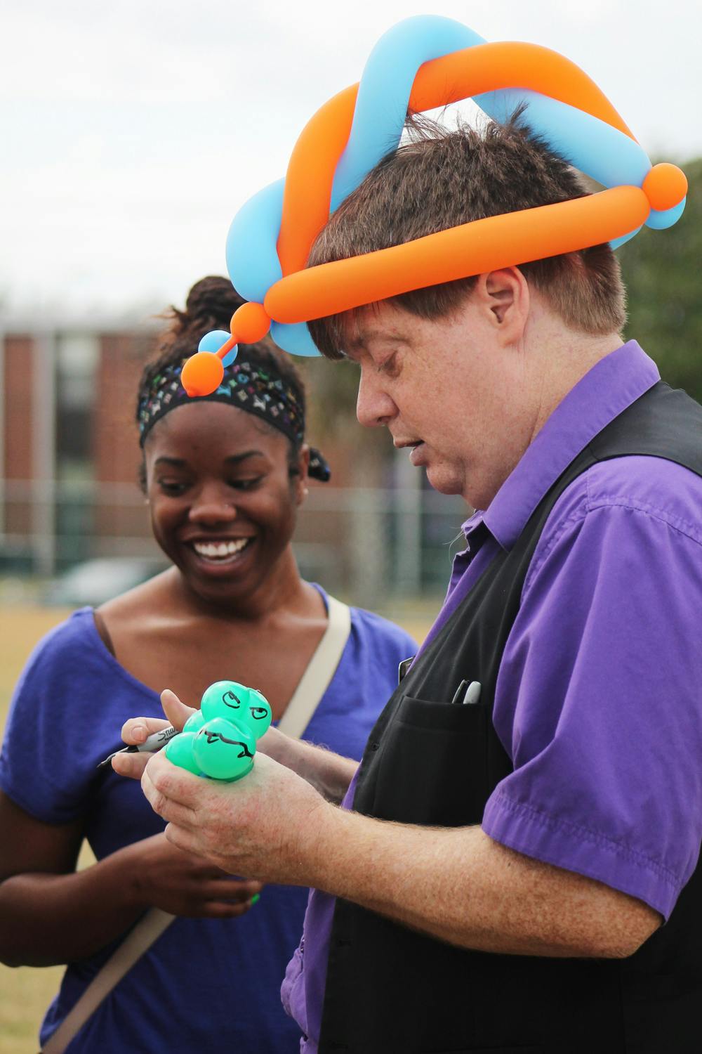 <p>Israel Taylor, an 18-year-old UF health science freshman, and her family watch as "Magic Mike" makes her a Gator balloon bracelet at the Family Fest and Barbecue Lunch during Family Weekend.</p>