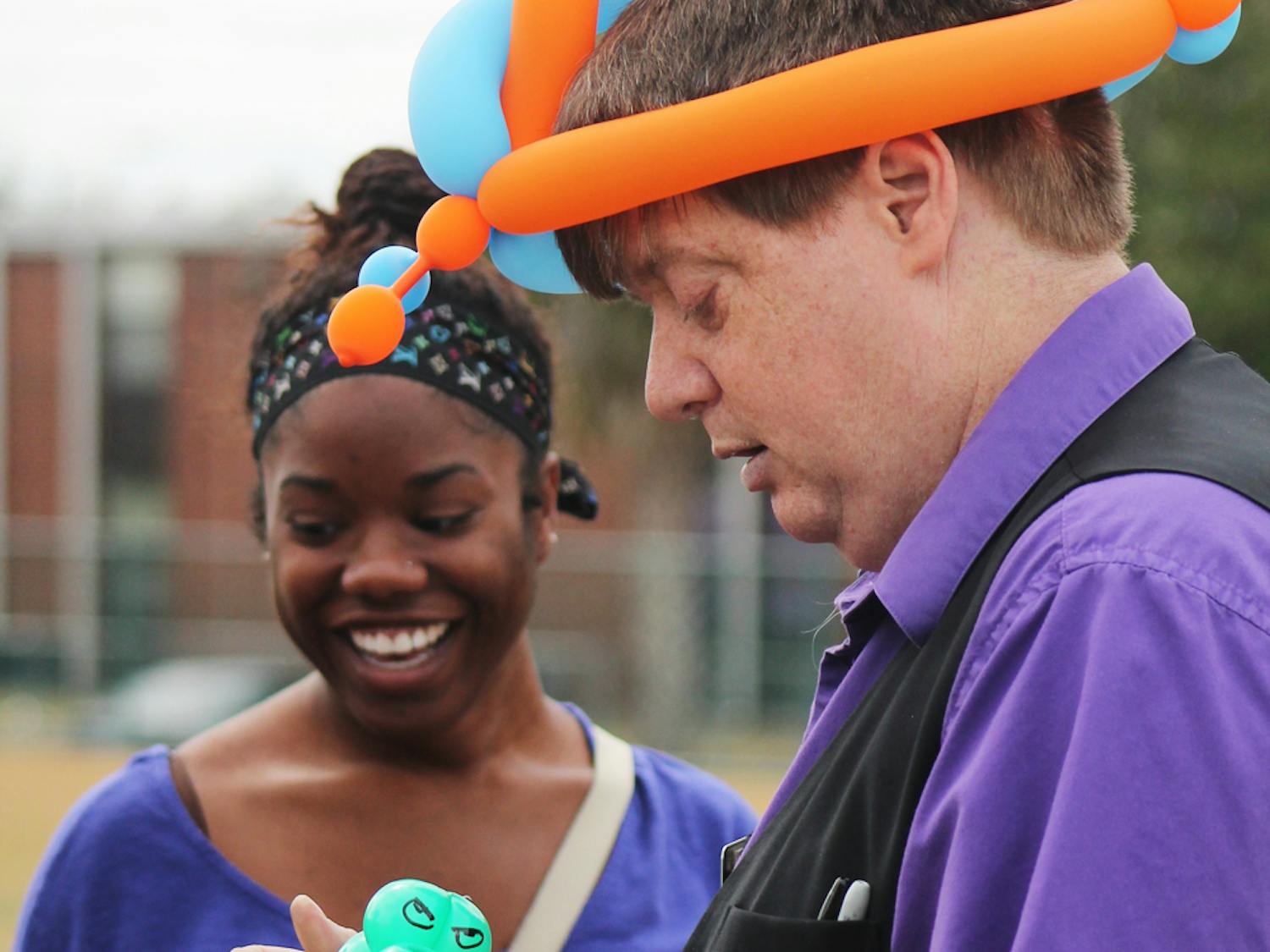 Israel Taylor, an 18-year-old UF health science freshman, and her family watch as "Magic Mike" makes her a Gator balloon bracelet at the Family Fest and Barbecue Lunch during Family Weekend.