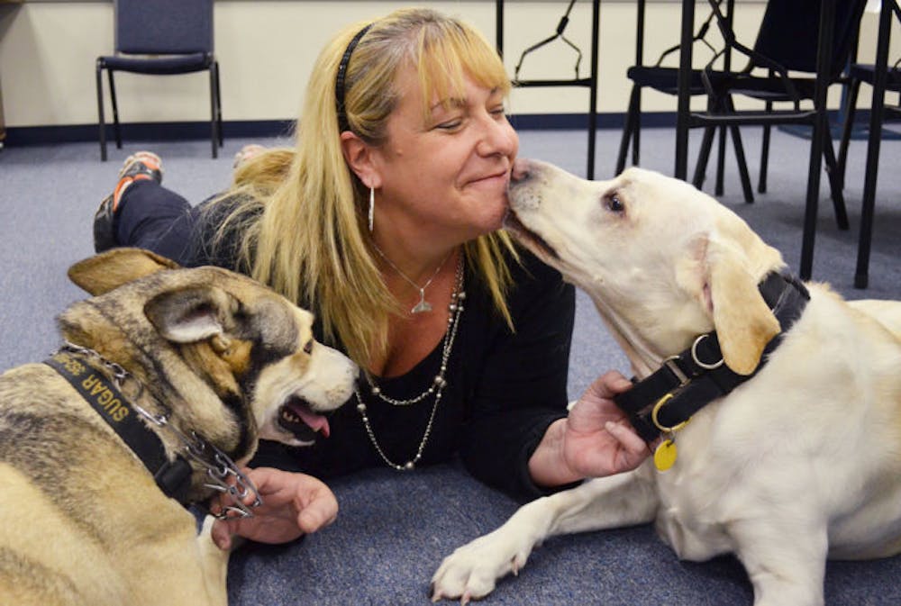 <p>Marcia Wolf-Deffense, 45, plays with her dogs Sugar, 7, and Spice, 6, in the UPD conference room Friday. The Humane Society has received about $500 in donations in memory of UPD Officer Jean-Guy Deffense.</p>