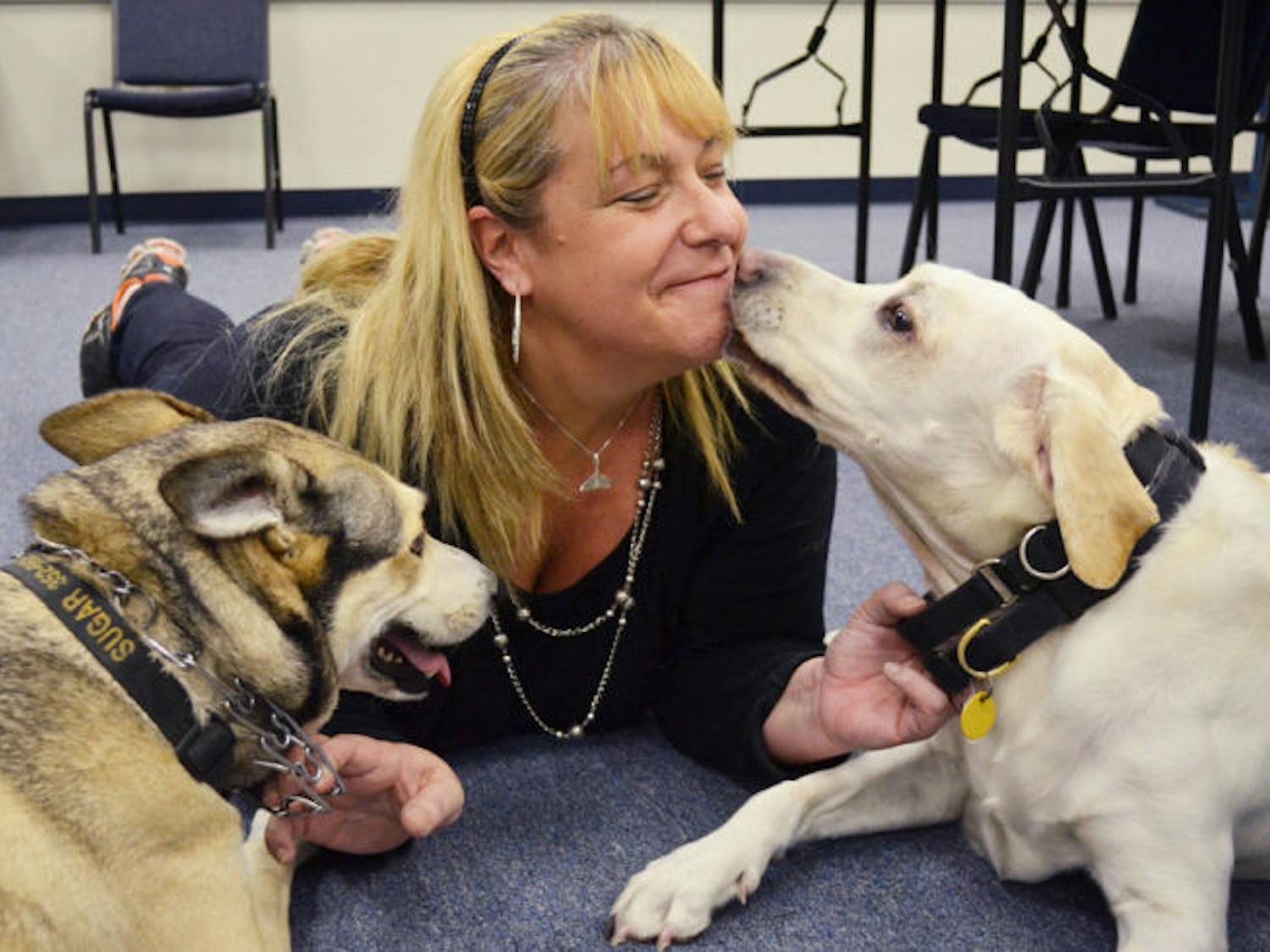 Marcia Wolf-Deffense, 45, plays with her dogs Sugar, 7, and Spice, 6, in the UPD conference room Friday. The Humane Society has received about $500 in donations in memory of UPD Officer Jean-Guy Deffense.