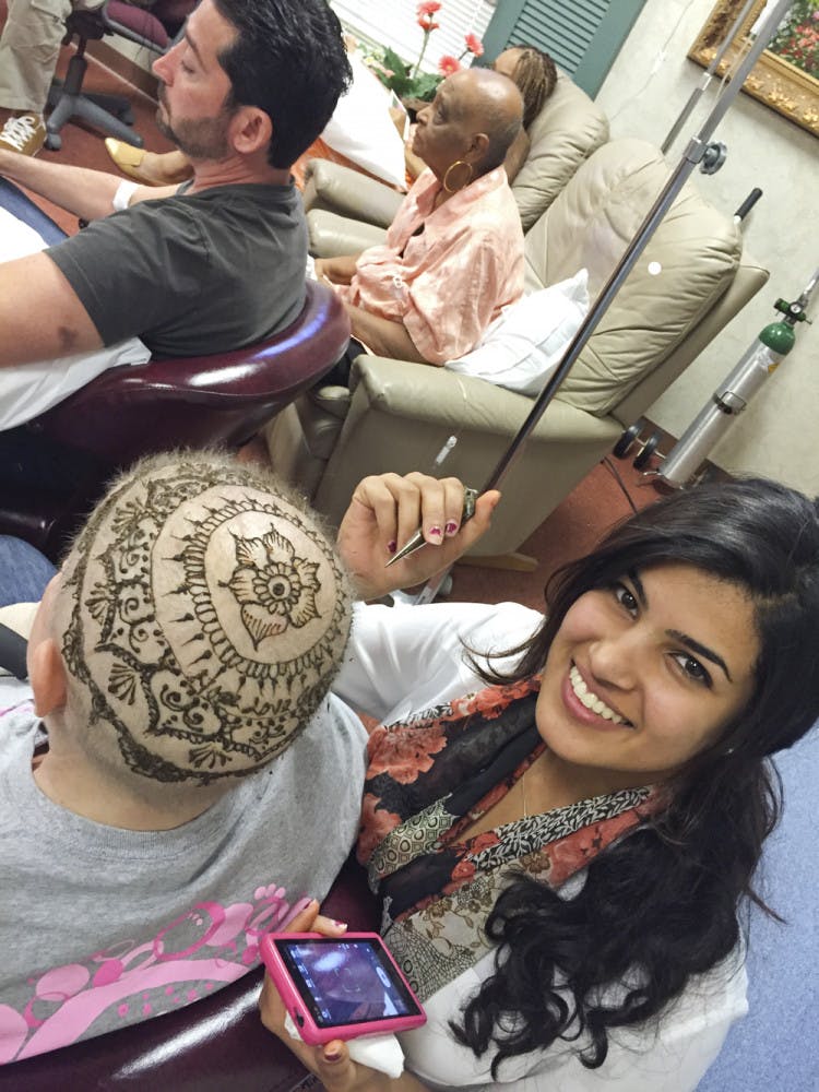 UF religion senior Jeena Kar, 21, paints henna on a woman’s head during a cancer support group session at a private medical practice in Orlando. 