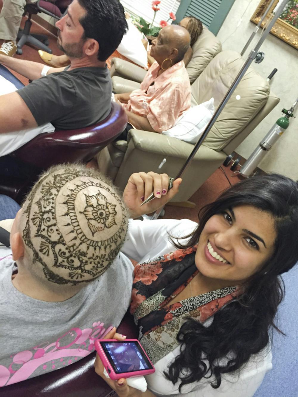 <p class="p1">UF religion senior Jeena Kar, 21, paints henna on a woman’s head during a cancer support group session at a private medical practice in Orlando. </p>