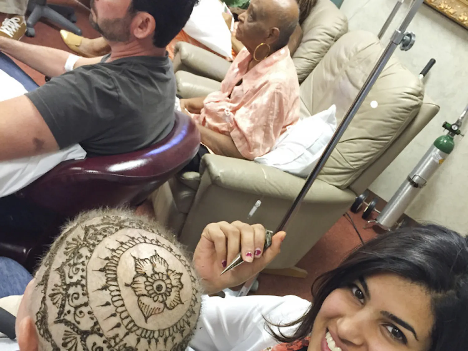 UF religion senior Jeena Kar, 21, paints henna on a woman’s head during a cancer support group session at a private medical practice in Orlando.