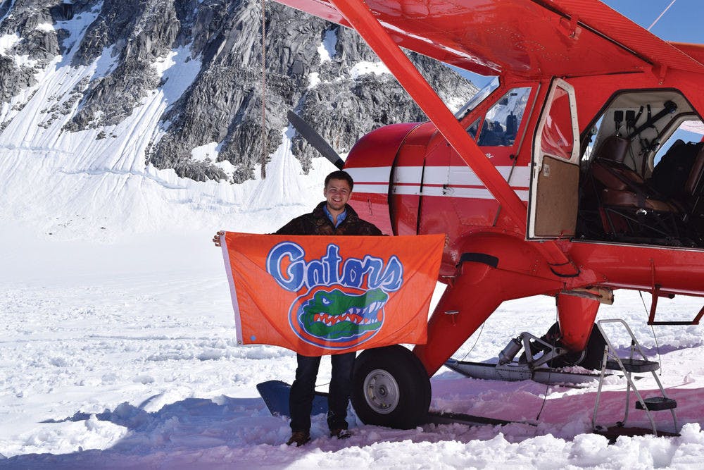 <p class="p1">UF electrical engineering senior Kyle Johnson, 22, holds up a Gator flag on Mount McKinley.</p>