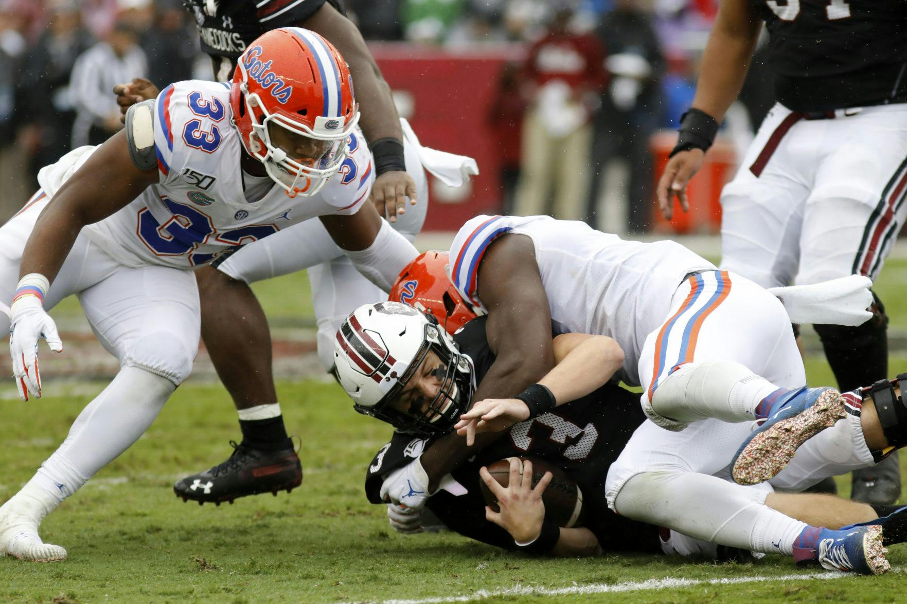 South Carolina's Ryan Hilinski, bottom, gets sacked by Florida's Zachary Carter, right, in the first half of an NCAA college football game Saturday, Oct. 19, 2019, in Columbia, SC. Florida defeated South Carolina 38-27.