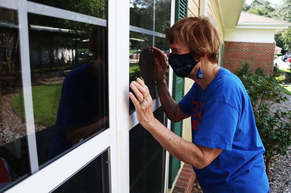 Patsy Nelms waves to her husband, Warren Nelms, through his window in the assisted living building at Oak Hammock on Wednesday, Oct. 14, 2020. She cannot go inside.