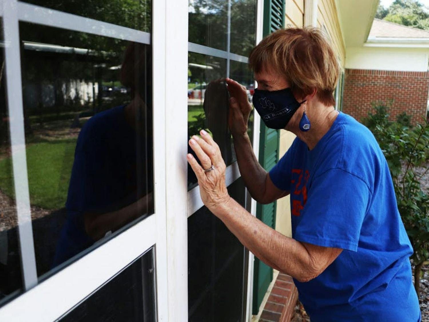 Patsy Nelms waves to her husband, Warren Nelms, through his window in the assisted living building at Oak Hammock on Wednesday, Oct. 14, 2020. She cannot go inside.