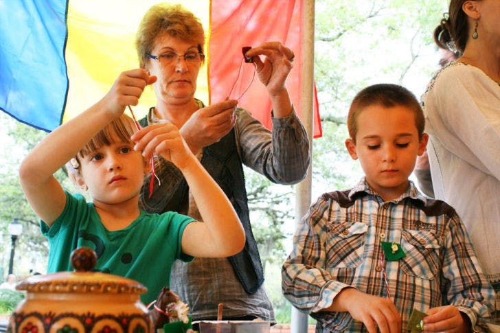 Camelia Moisescu, of Romania, makes martisors with her grandchildren — Stefanie, 6, and Michael, 8 — at the Viva Europe! festival in downtown Gainesville on Saturday. Women wear these pins during March to symbolize the coming of spring.