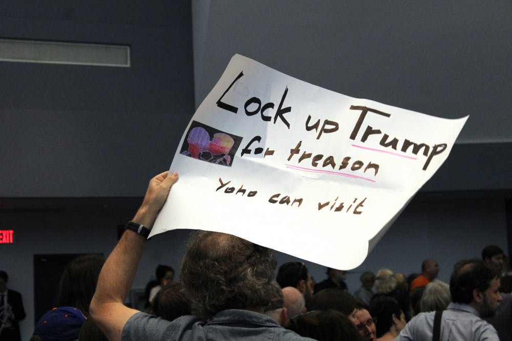A man holds up a sign reading "Lock up Trump for treason, Yoho can visit" at the town hall meeting with Ted Yoho. The mood from many of the attendees was contrarian, as they were displeased with Yoho's actions in D.C. 