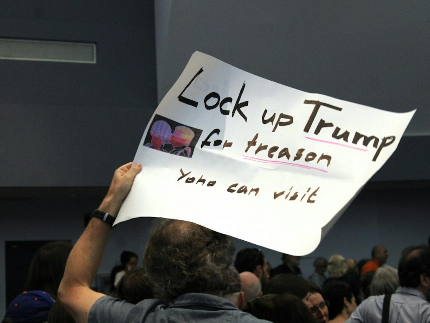 A man holds up a sign reading "Lock up Trump for treason, Yoho can visit" at the town hall meeting with Ted Yoho. The mood from many of the attendees was contrarian, as they were displeased with Yoho's actions in D.C. 