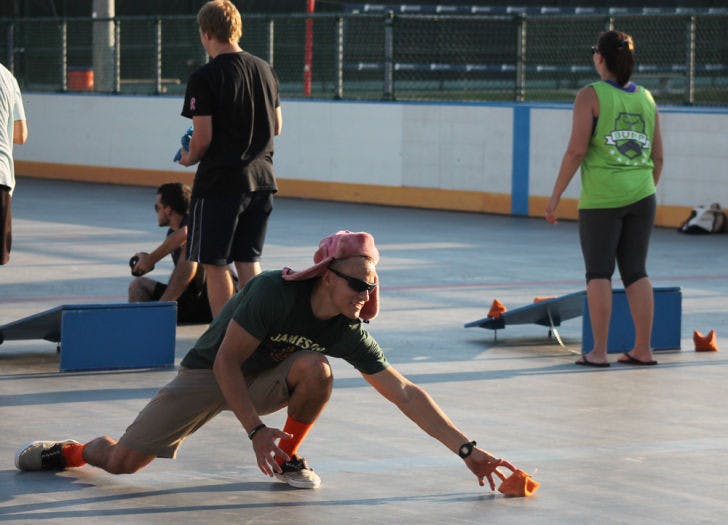 Business administration senior Michael Sully, 22, crouches to catch a beanbag during the last few rounds of the Cornhole Tournament at Broward Outdoor Recreation Center on Friday afternoon.