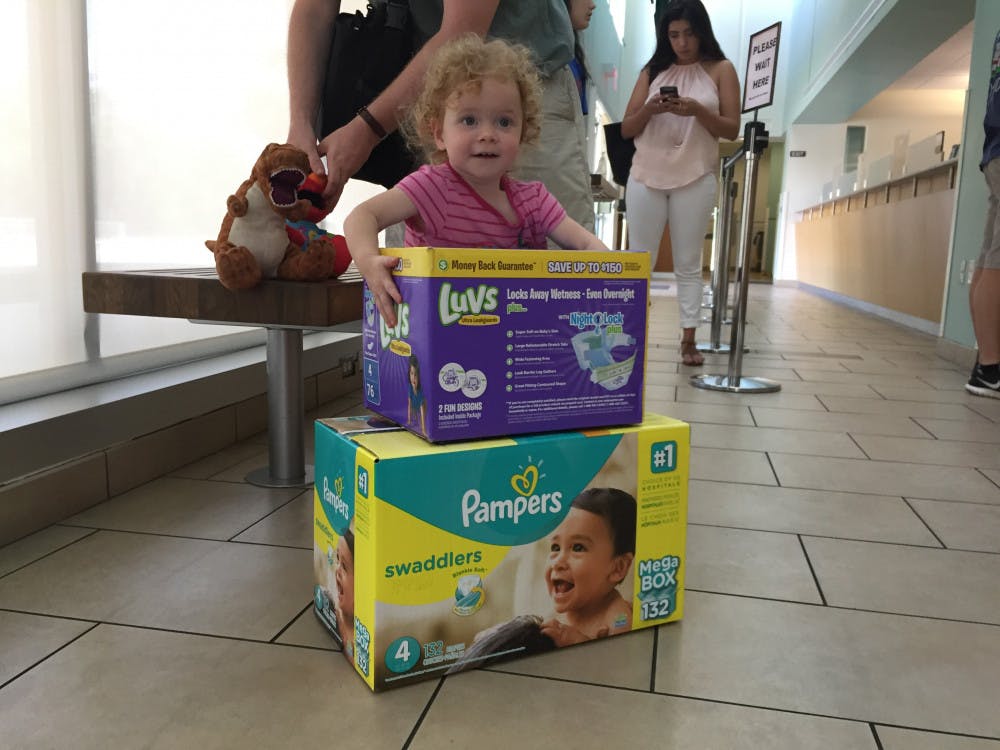 <p>Two-year-old Isobel Vincent picks up a box of diapers at the UF Transportation and Parking Services office Wednesday afternoon. Employees donated two boxes of diapers to her and her parents after her father, Michael Vincent, a 33-year-old UF PhD musicology candidate, tweeted at UF President Kent Fuchs about the “Food for Fines” program.</p>