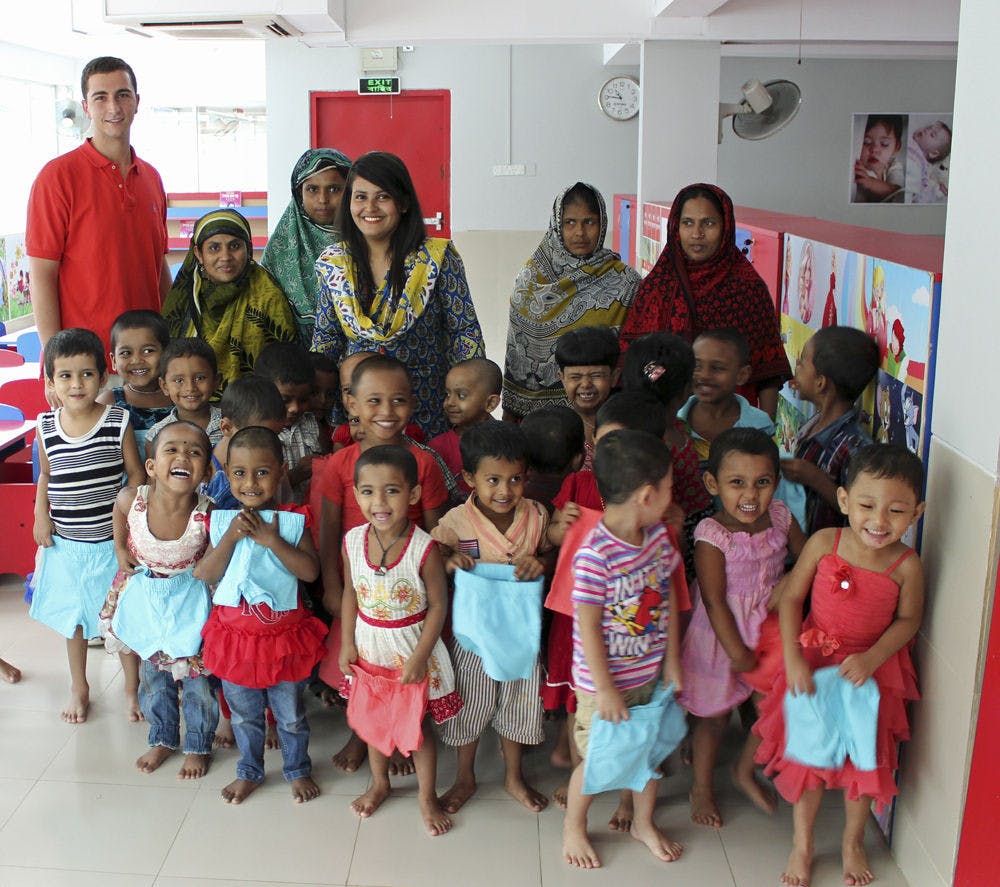 <p>Robert Felder (far left) poses for a photo at the factory day care in Bangladesh on June 3, 2015. The 21-year-old said he founded his company, which donates paris of shorts to children in poverty, after visiting a local clothing factory.</p>