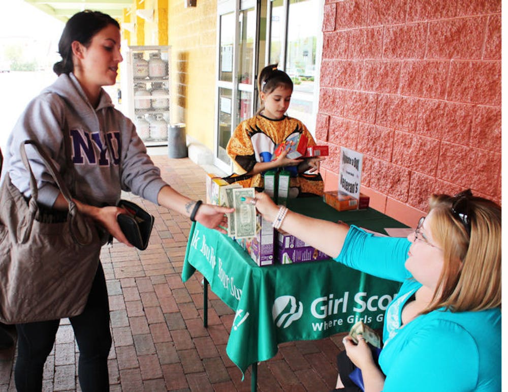 <p>Michelle Manzione, a 23-year-old UF telecommunication senior, pays Sara Barner-Rasmussen, 32, while Nissa Barner-Rasmussen, 9, gathers cookies Monday at the Publix on 34th Street and Williston Road.</p>