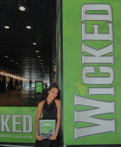 Larson standing outside the Gershwin Theatre holding “Wicked” production binder.